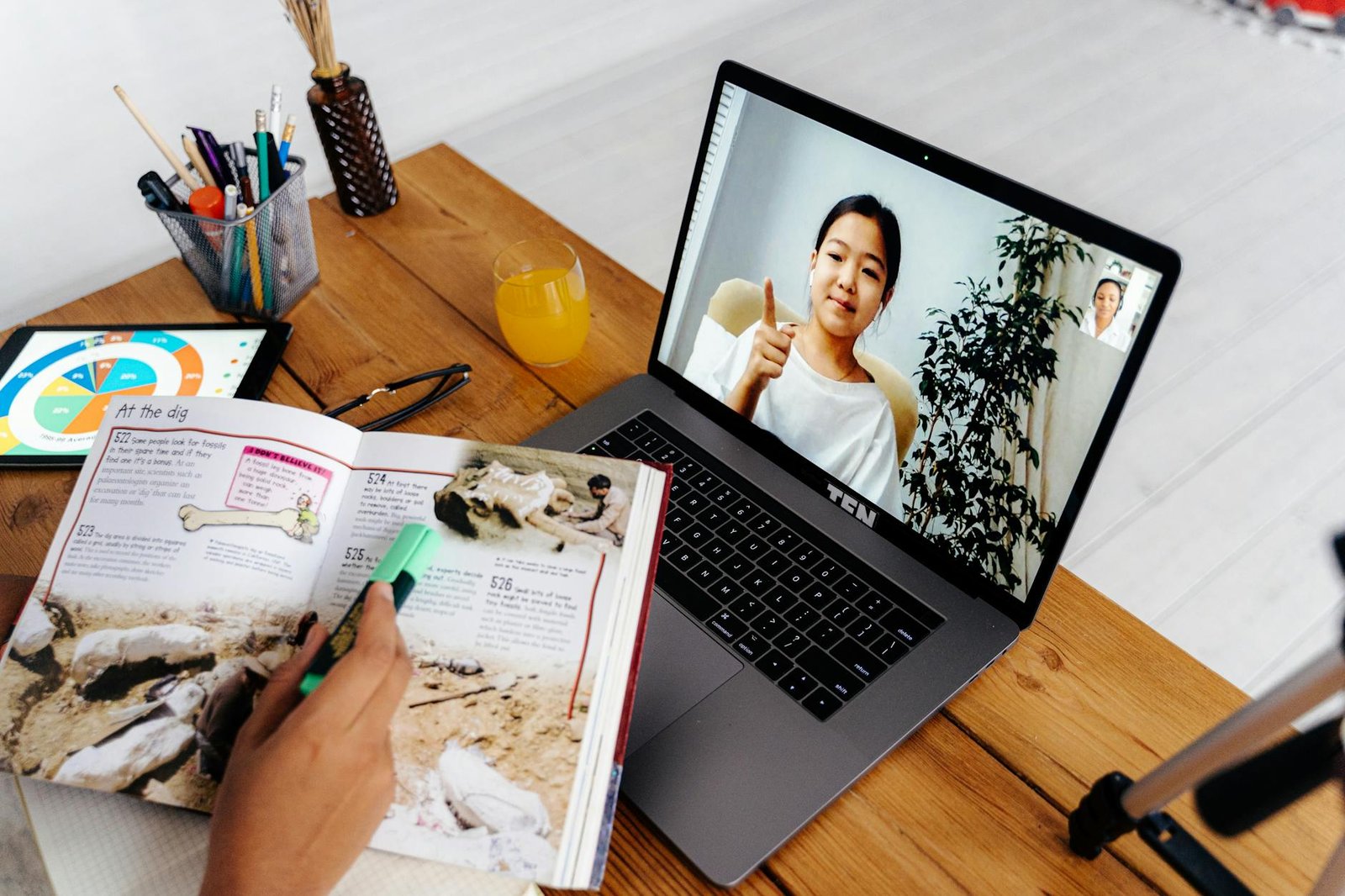 關於椰菲 Online teaching session with digital tools, featuring a woman on a laptop screen and educational materials.